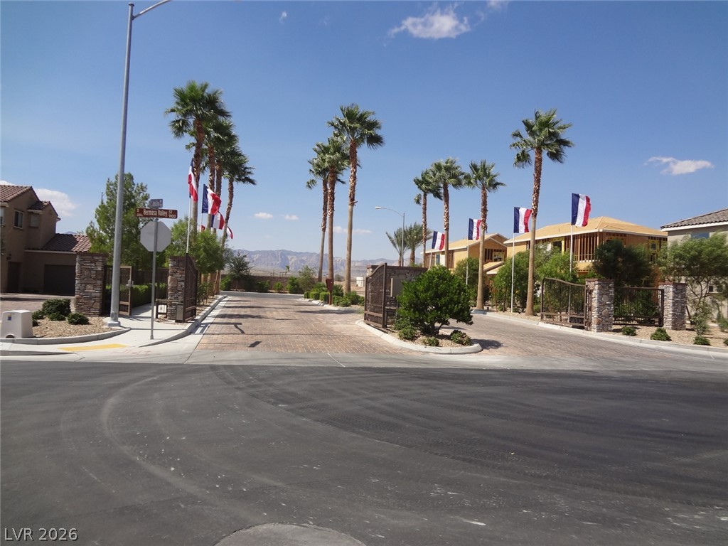 9453 Alma Ridge Avenue Las Vegas, NV 89178 - Photo 25 of 25 Secure community entrance with palm-lined streets, offering mountain views and lush landscaping.