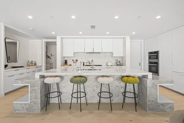 a large white kitchen with a large window and stainless steel appliances