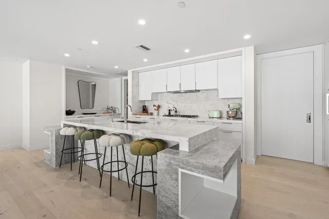a large kitchen with stainless steel appliances kitchen island granite countertop a large stove a sink dishwasher and white cabinets with wooden floor