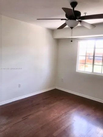 an empty room with a ceiling fan and windows