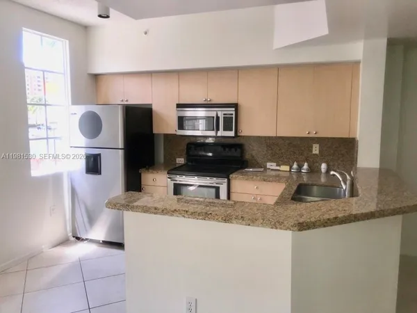 a kitchen with granite countertop a sink a stove top oven a counter space and cabinets