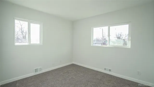 an empty room with windows and cabinet