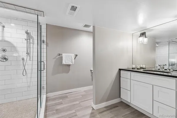a bathroom with a granite countertop sink a mirror and shower