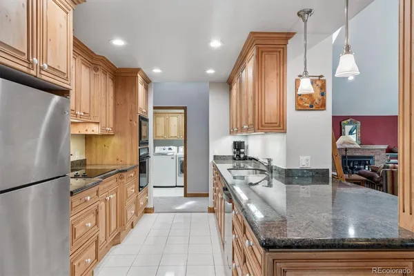 a kitchen with stainless steel appliances granite countertop a refrigerator a stove and a sink