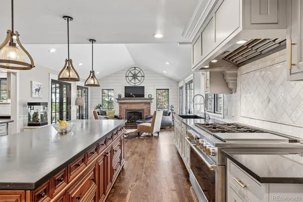 a open kitchen with stainless steel appliances granite countertop a stove a sink dishwasher a dining table and chairs with wooden floor