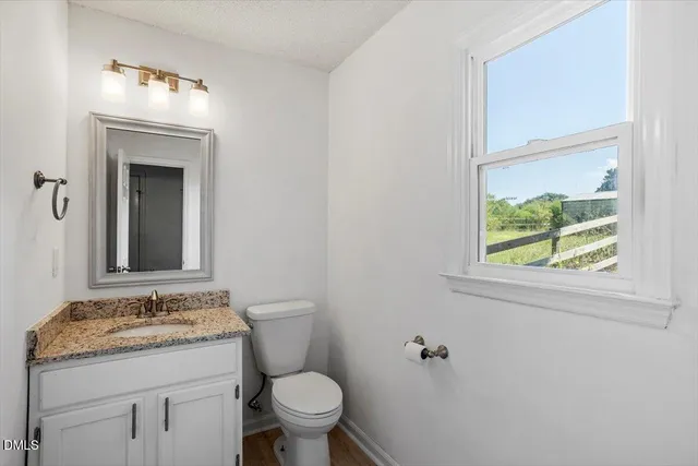 a bathroom with a granite countertop sink toilet and mirror
