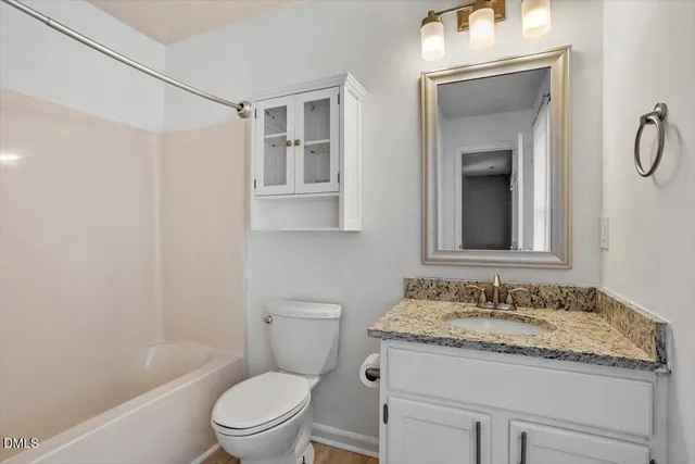 a bathroom with a granite countertop sink toilet a mirror and shower