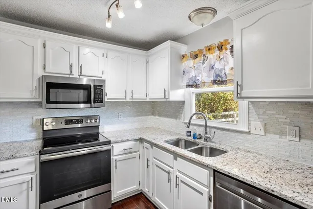 a kitchen with stainless steel appliances granite countertop a sink a stove and microwave