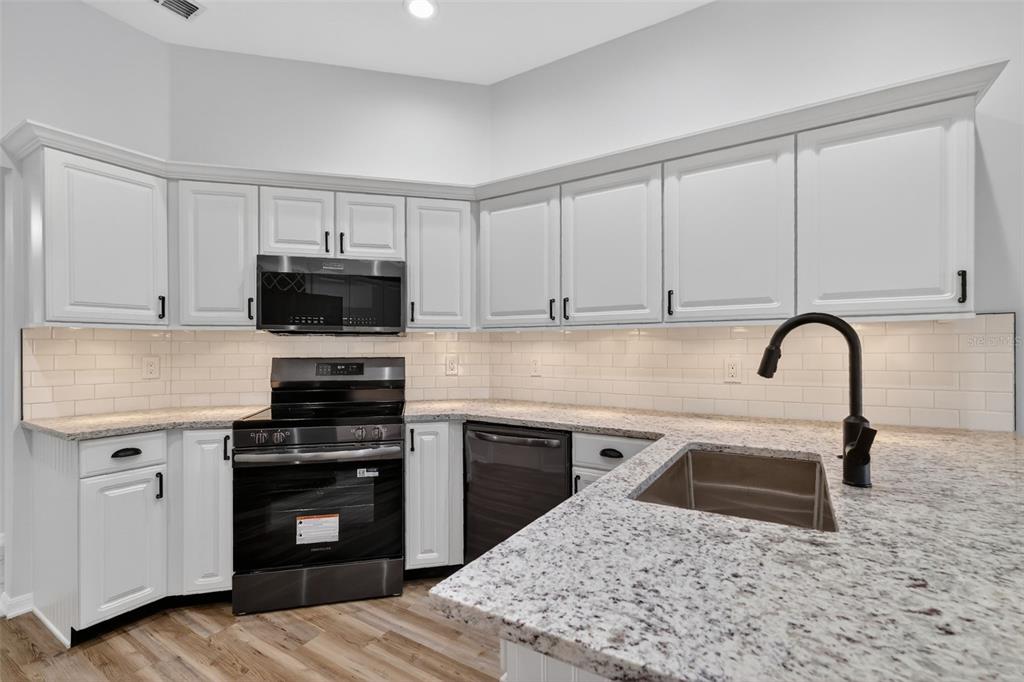 6027 Spring Creek Court Mount Dora, FL 32757 - Photo 13 of 42 a kitchen with sink a microwave and cabinets