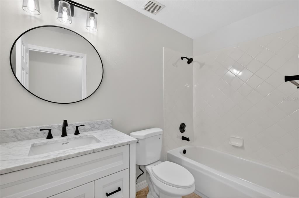 6027 Spring Creek Court Mount Dora, FL 32757 - Photo 24 of 42 a bathroom with a toilet a sink a mirror and bathtub