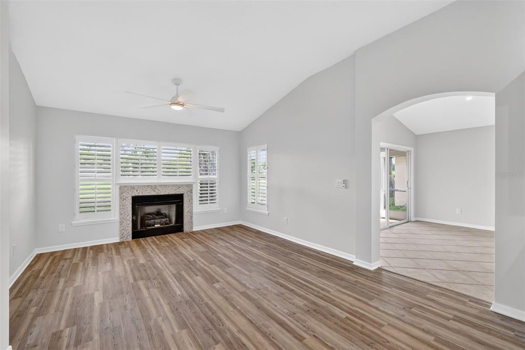 6027 Spring Creek Court Mount Dora, FL 32757 - Photo 9 of 42 an empty room with wooden floor fireplace and windows