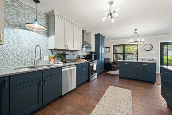 a kitchen with stainless steel appliances kitchen island granite countertop a sink dishwasher a stove a refrigerator and cabinets with wooden floor