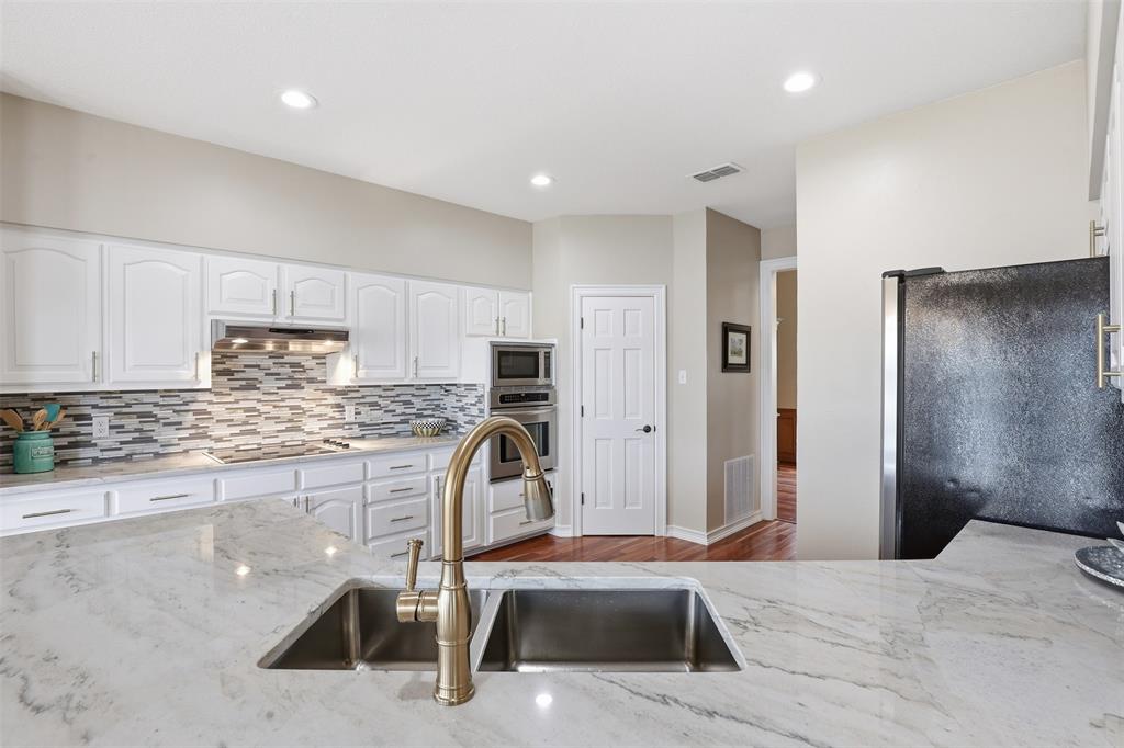 2406 River Road Granbury, TX 76048 - Photo 13 of 40 a kitchen with stainless steel appliances granite countertop a sink refrigerator and cabinets