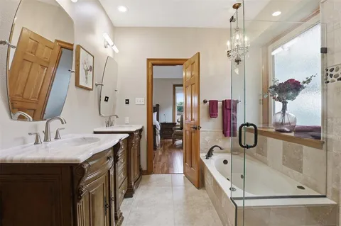 a spacious en suite bathroom with a granite countertop tub sink and mirror