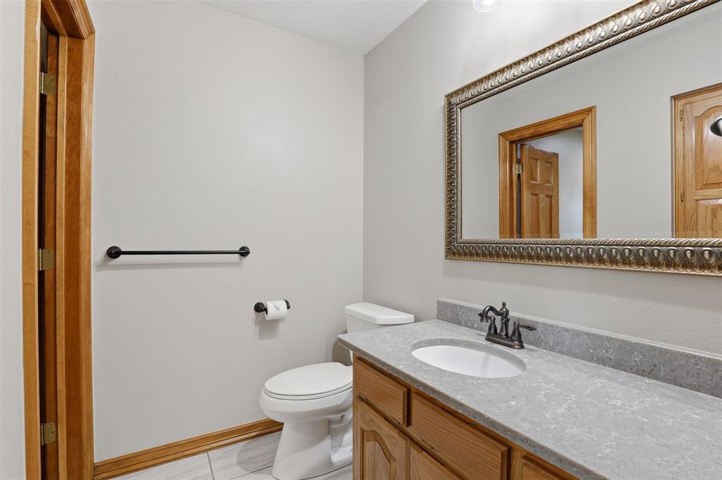 2406 River Road Granbury, TX 76048 - Photo 21 of 40 a bathroom with a granite countertop sink toilet and mirror