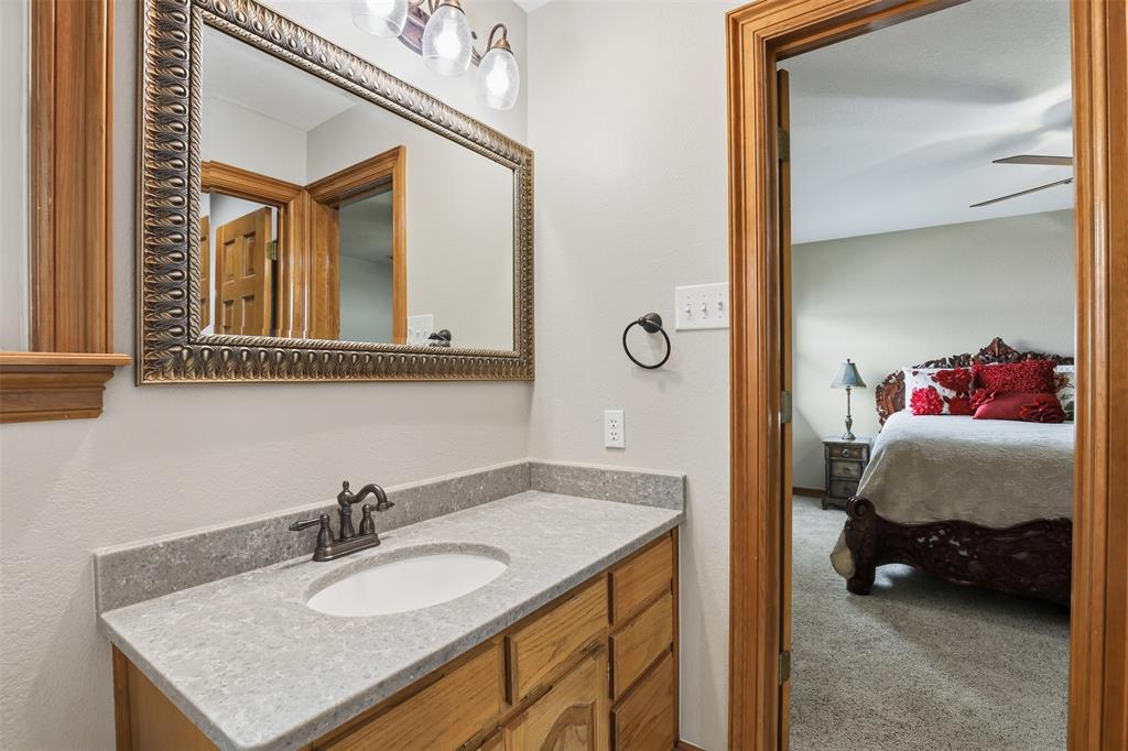 2406 River Road Granbury, TX 76048 - Photo 24 of 40 a en suite bathroom with a granite countertop sink and a mirror