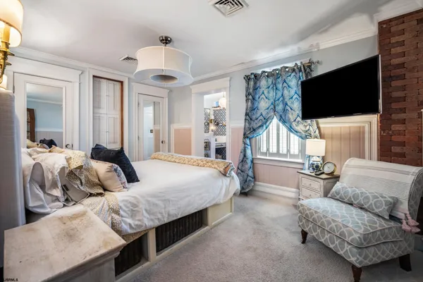 a bedroom with a large bed and a flat tv screen