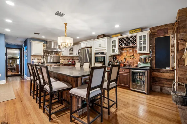 a dining room with wooden floor a chandelier a wooden table and chairs