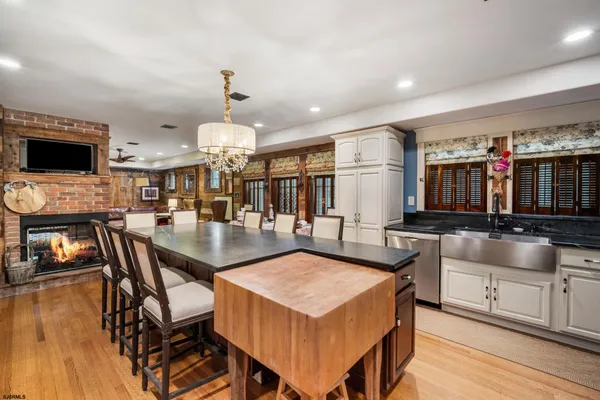 a living room with stainless steel appliances kitchen island granite countertop a table chairs and a flat screen tv
