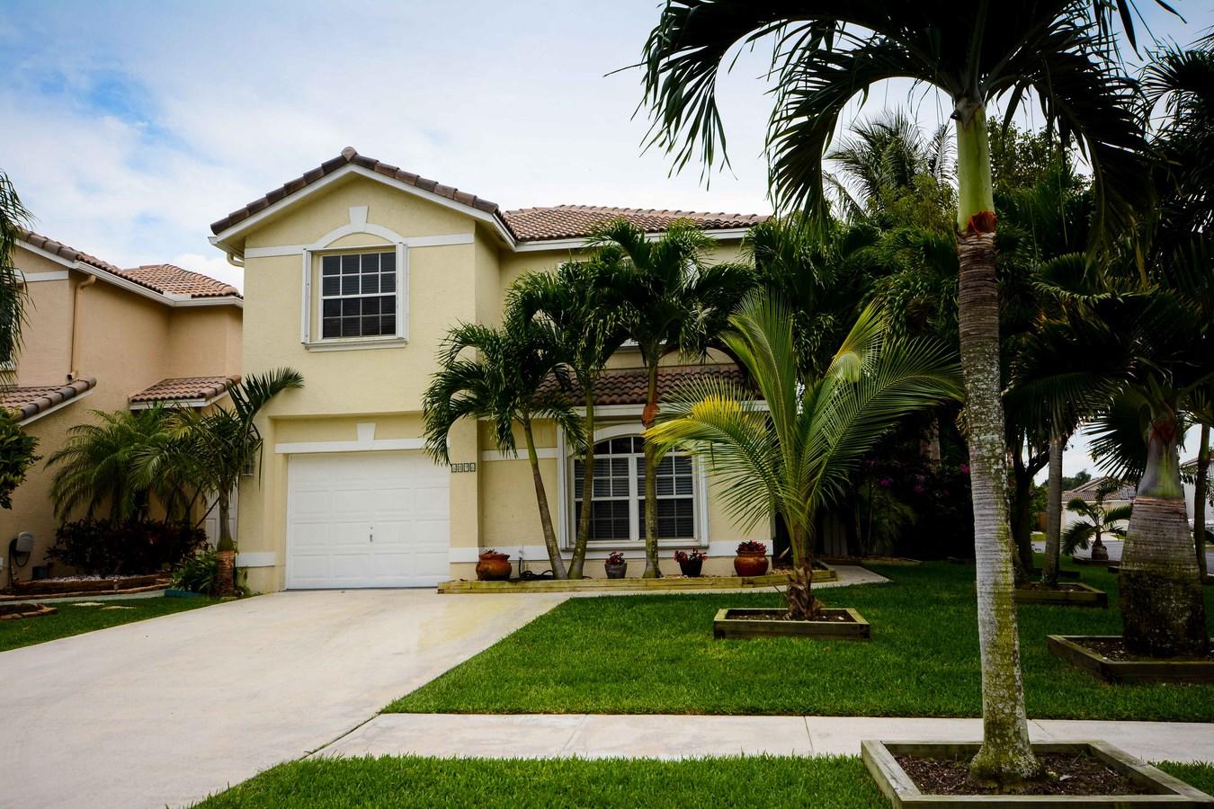 6896 Long Key Street Lake Worth, FL 33467 - Photo 2 of 18 a view of a house with a yard and palm trees