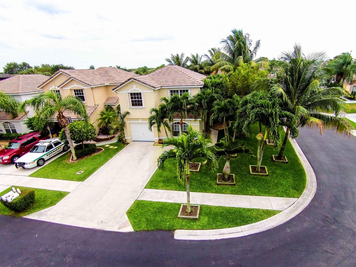 6896 Long Key Street Lake Worth, FL 33467 - Photo 4 of 18 a view of a white house with a swimming pool and lawn chairs under an umbrella