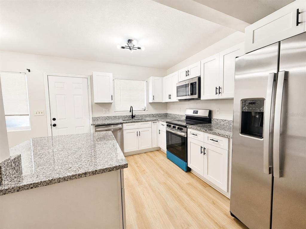 1353 Lakeview Road Clearwater, FL 33756 - Photo 5 of 15 a kitchen with granite countertop white cabinets and white appliances