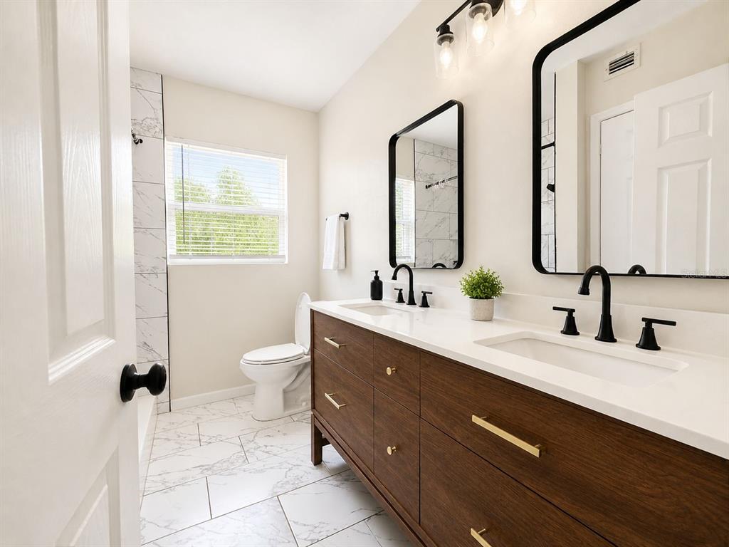 1353 Lakeview Road Clearwater, FL 33756 - Photo 8 of 15 a bathroom with a double vanity sink toilet and a mirror
