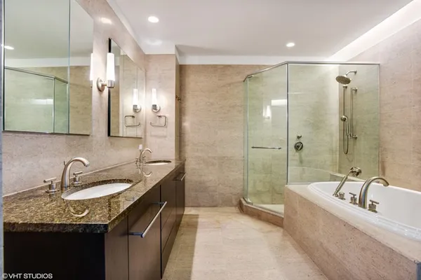 a bathroom with a granite countertop double vanity sink a mirror a bathtub and shower
