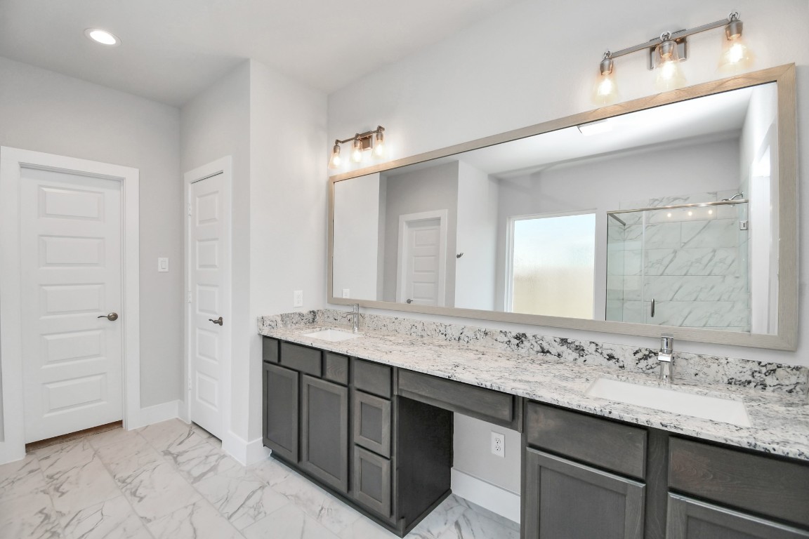 3123 Native Spg Drive Spring, TX 77373 - Photo 23 of 38 Escape to a spa-like oasis in this primary bathroom. Enjoy a walk-in shower with tile surround, a separate garden tub with custom detailing, and an elegant vanity featuring light countertops, modern hardware, and beautiful vanity lights. Experience luxury and relaxation in every detail. Sample photo of completed home with similar floor plan. Actual colors and selections may vary.
