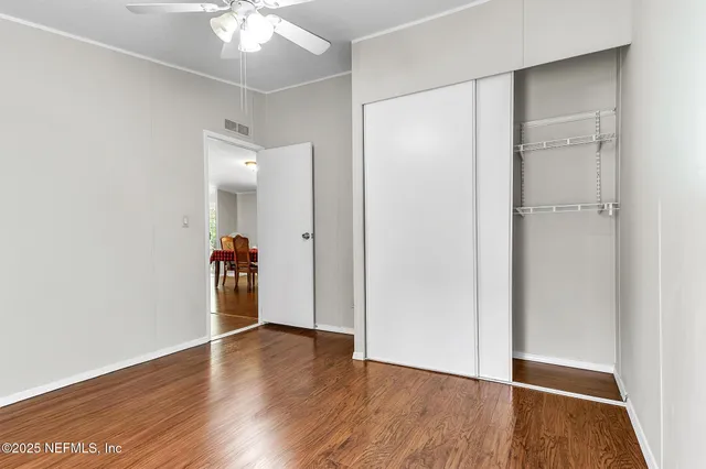 an empty room with wooden floor and a ceiling fan
