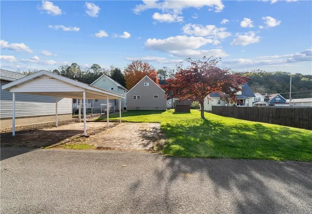 a view of a house with a big yard and large trees