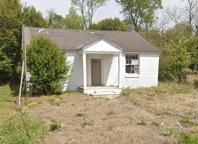 a view of a house with a yard and large tree
