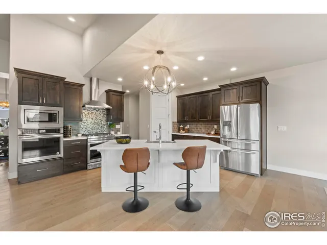 a kitchen with stainless steel appliances kitchen island granite countertop a refrigerator a stove a sink a oven with a dining table and chairs
