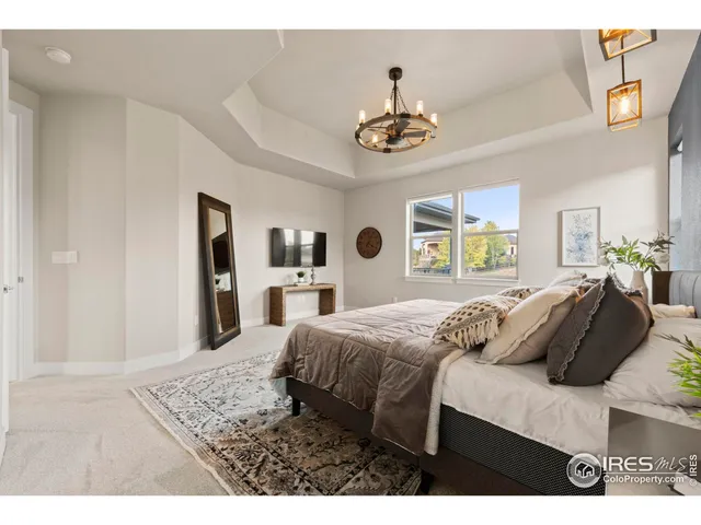 a bedroom with a bed a chandelier and flat screen tv