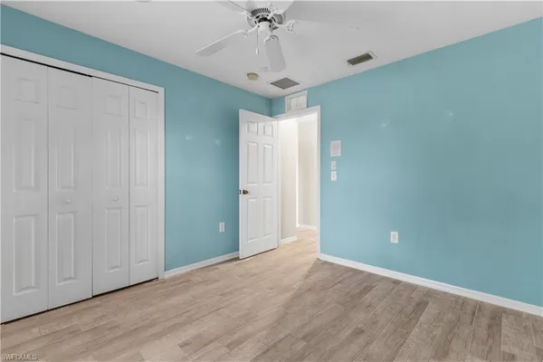 an empty room with a chandelier fan and wooden floor