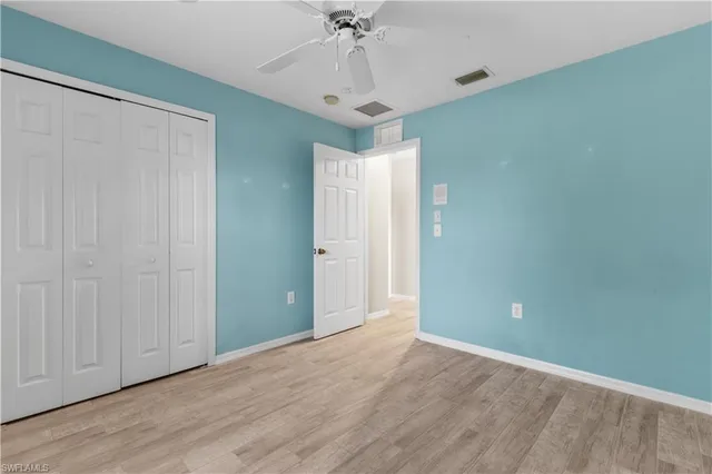 an empty room with a chandelier fan and wooden floor