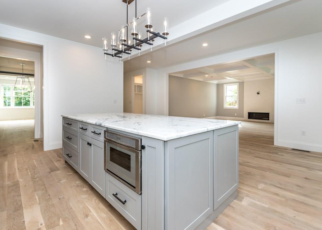 56 Pershing Road Needham, MA 02494 - Photo 10 of 42 a hall with kitchen island a chandelier wooden floor and a living room
