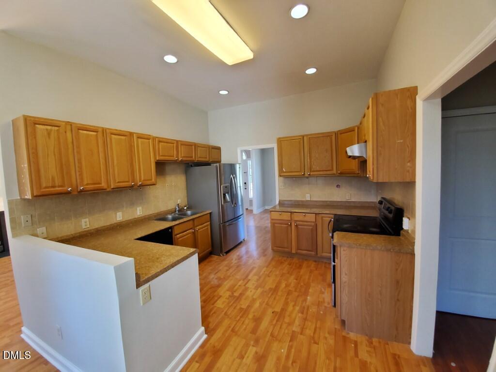 8007 Sundance Circle Durham, NC 27713 - Photo 4 of 23 a kitchen with stainless steel appliances granite countertop a sink a stove a refrigerator cabinets and wooden floor