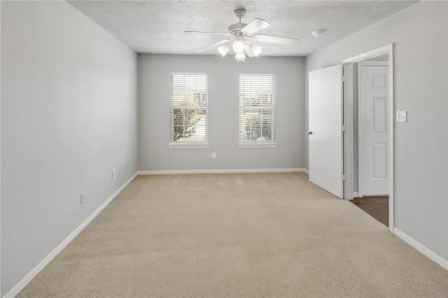 an empty room with chandelier fan and windows