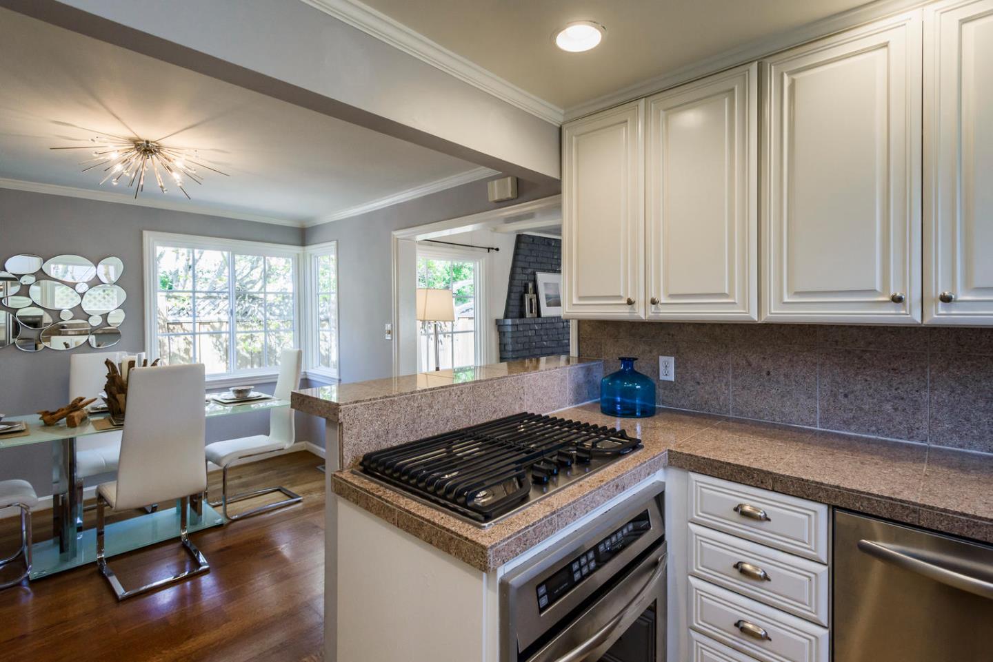 117 Dwight Road Burlingame, CA 94010 - Photo 11 of 20 a kitchen with granite countertop a stove a sink dishwasher and white cabinets with wooden floor