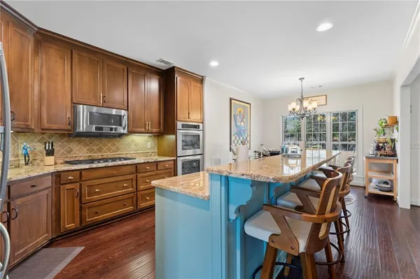 a view of a kitchen with kitchen island granite countertop wooden floors and stainless steel appliances
