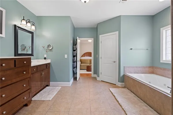 a spacious bathroom with a tub sink and mirror
