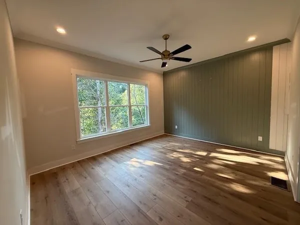 a view of empty room with wooden floor and fan