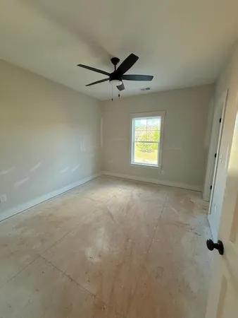 an empty room with windows and fan