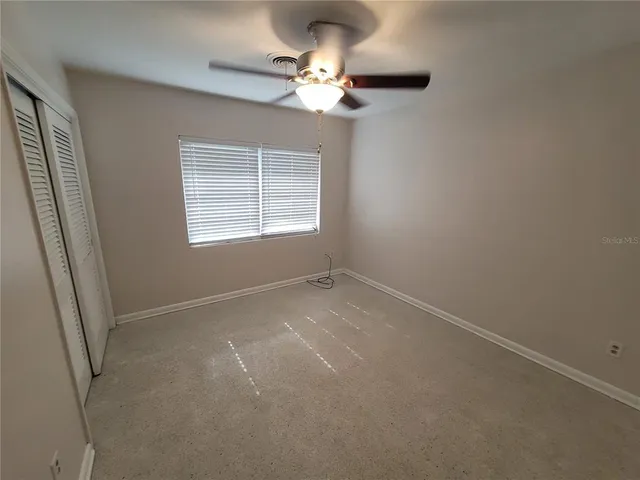 en empty room with windows and ceiling fan