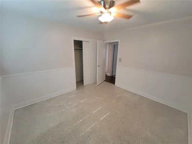 a view of an empty room and chandelier fan