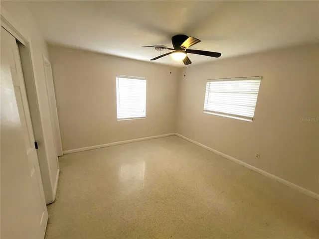 an empty room with windows and fan