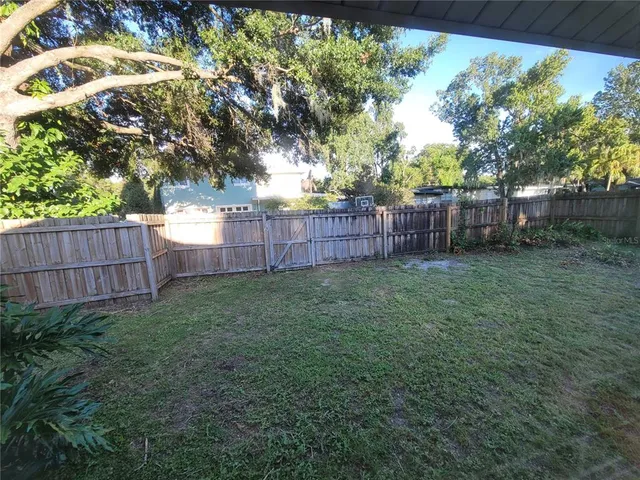 a view of a backyard with a trees and wooden fence