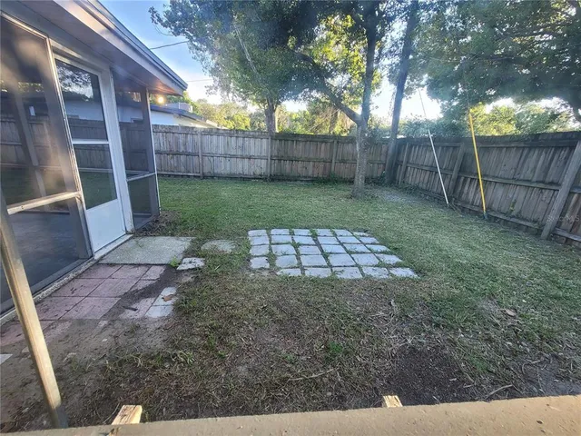 a view of a backyard with a large tree and wooden fence