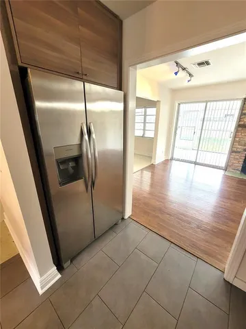 a view of a refrigerator in kitchen and an empty room